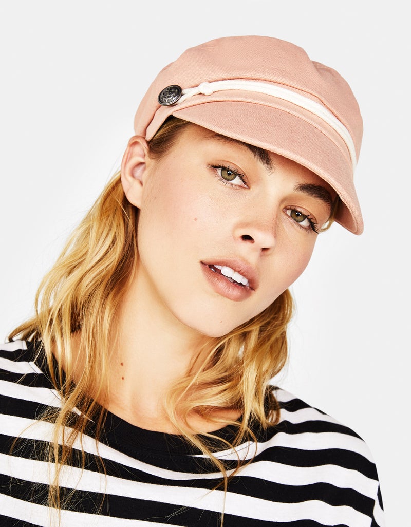 En Bershka tenemos las dos opciones clásicas de la gorra marinera: la imitación a piel y la azul marino. Además, hay una versión preciosa de color de rosa con los dos preceptivos botones de ancla a cada lado.