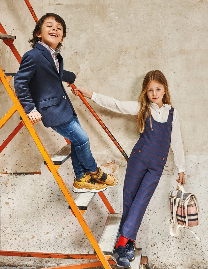 Rodrigo lleva camisa de Hackett, chaqueta de Tizzas para El Corte Inglés, pantalón de Primark y zapatos de Primigi. Claudia, camisa de Nícoli, peto de Gocco, calcetines de Calcedonia, zapatillas de Merkal y mochila de Zara.