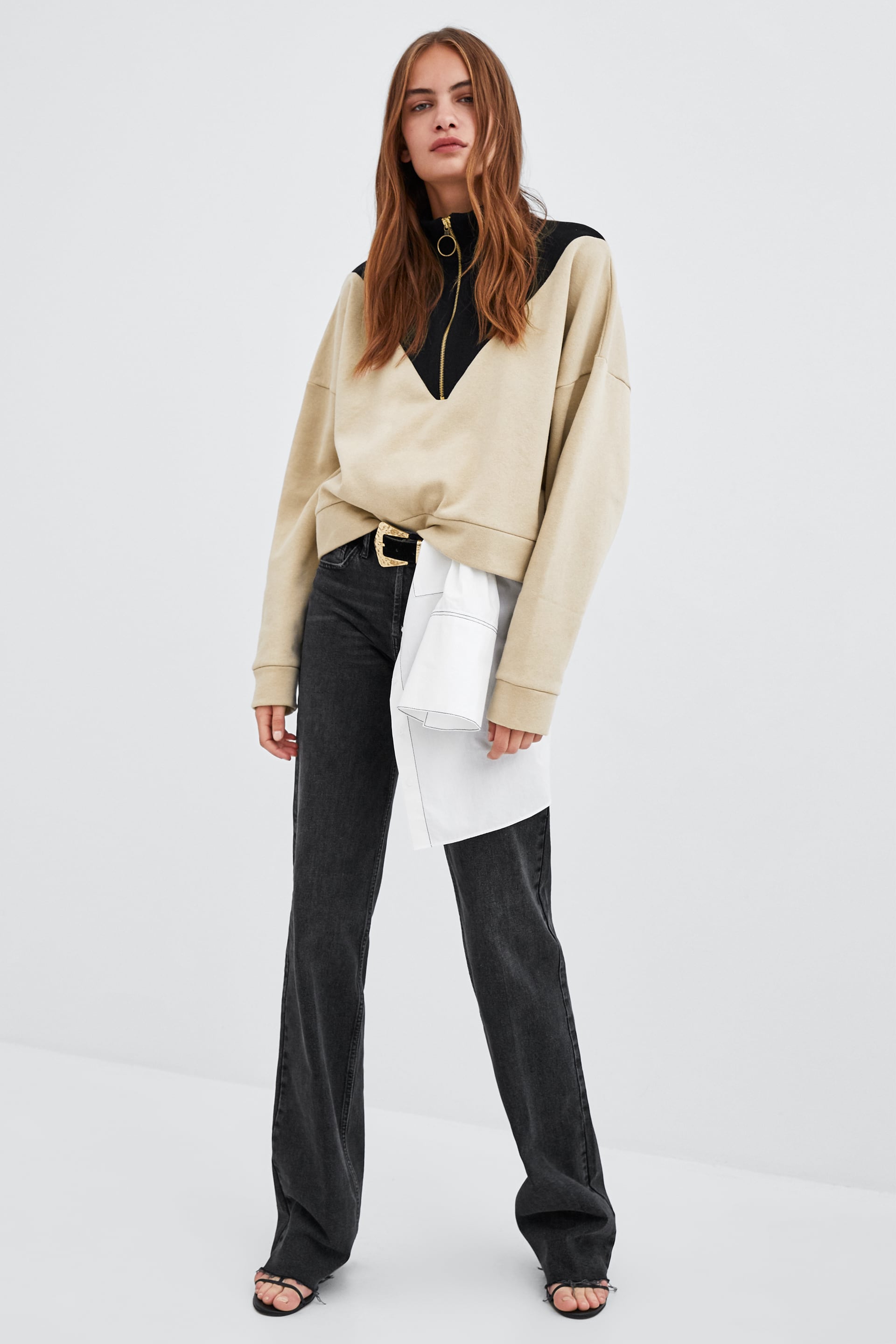 En Zara la camisa blanca asoma por debajo de al sudadera con algo más de atrevimiento.