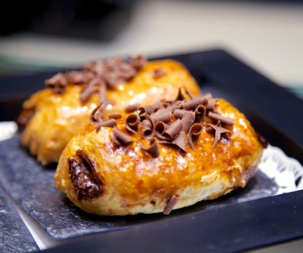 Ingredientes: 1 lámina de hojaldre rectangular, crema de chocolate, mermelada de melocotón y fideos de chocolate.Paso a paso: 1. Extiende la lámina de hojaldre sobre una superficie lisa y unta la crema de chocolate en el centro de la masa.2. Para cerrar el hojaldre, dobla un extremo del hojaldre hasta el centro de la lámina y el otro extremo hacia el centro también. De este modo lograremos hacer los sacos rellenos de chocolate típicos de la napolitana.3. Ahora deberemos dar la vuelta a la pasta doblada para que el cierre de la napolitana de chocolate quede en la parte inferior; para conseguir hacer las napolitanas, deberemos cortar la masa en de forma rectangular para que quede la forma.4. Introduce las napolitanas de chocolate en el horno previamente calentado a una temperatura de 200ºC durante 15 minutos.5. Sácalas del horno y unta mermelada de melocotón previamente calentada en el microondas con la ayuda de un pincel.