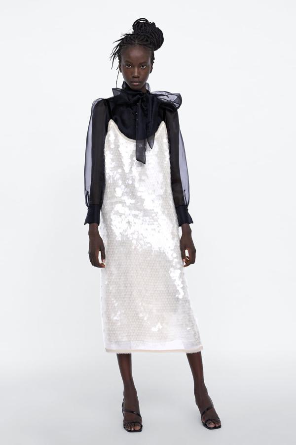 ¿Ir a la una boda de blanco? Sí, si es con esta combinación maestra de Zara que superpone un maravilloso vestido de lentejuelas blanco (59.95 euros) con  la blusa más bonita de la colección  (39.95 euros).