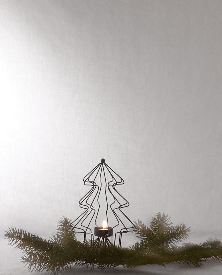 Cualquier rincón es bueno para poner un árbol de Navidad, aunque sea un portavelas en forma de abeto como este (9.99 euros) decorado con unas ramas naturales.