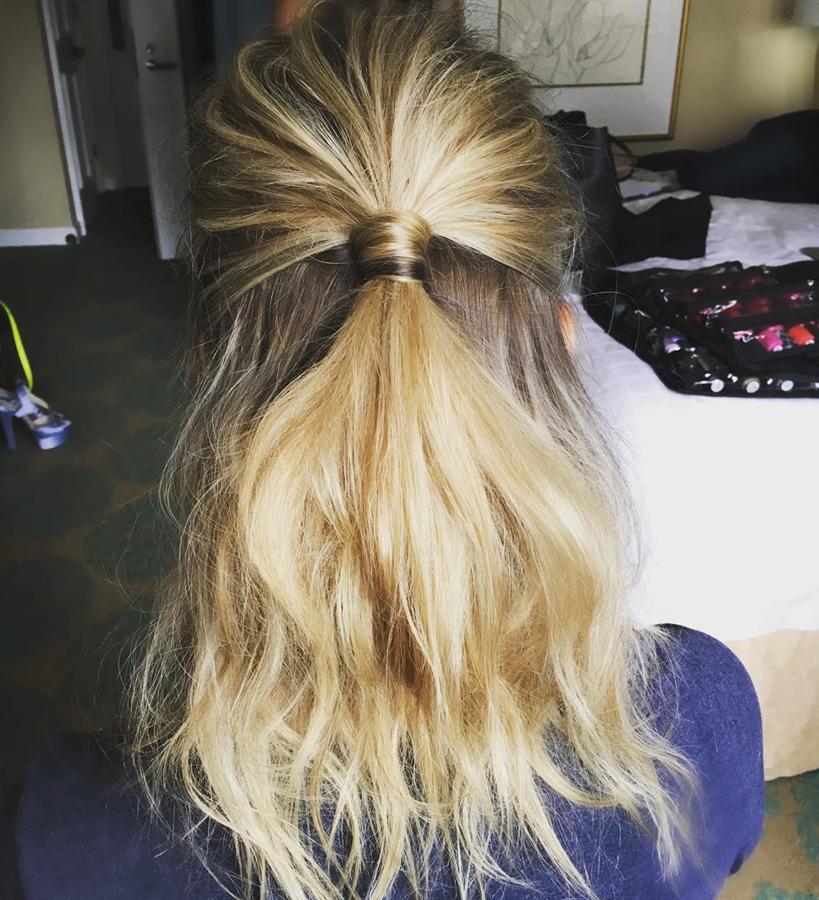 A pesar de su sencillez, este peinado es elegante. Peina la parte superior de tu melena hacia atrás, asegurándote de dejar la parte de arriba ahuecada, y átala con un elástico. Termina envolviendo un mechó alrededor de la goma para que no se vea.. 