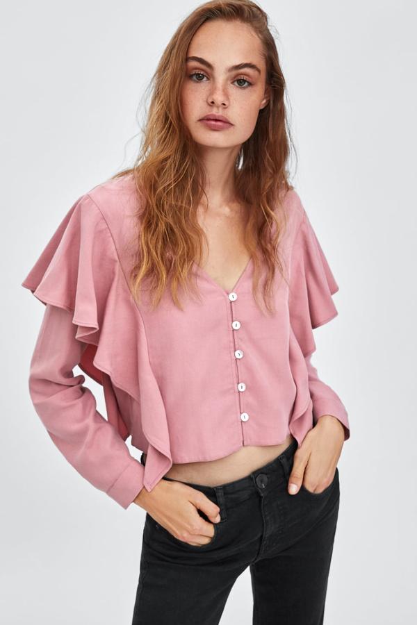 Una blusa ligeramente "oversize" adornada con dos grandes volantes frontales y botones metálicos en el cierre (Zara, 22,95 euros).