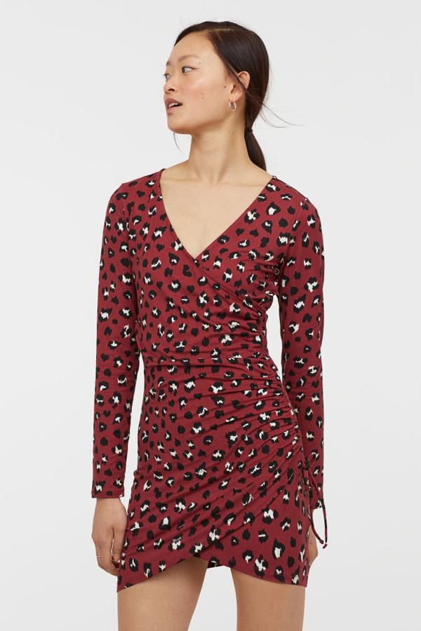 Vestido corto y entallado en punto suave, con escote de pico, parte delantera cruzada cosida con cordón de ajuste en un lateral, mangas largas y bajo asimétrico (24,99 euros).