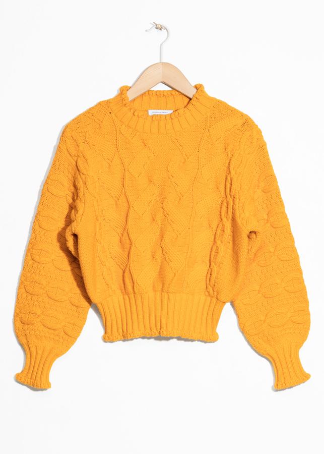 Un jersey confeccionado en punto grueso, con un dibujo enormemente intrincado y un color amarillo huevo que no pasa inadvertido. Además, lleva un mínimo volante en el cuello (47 euros).