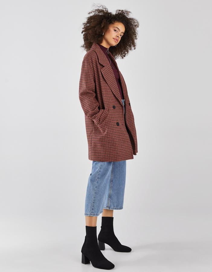 Abrigo largo de cuadros, con doble botonadura cruzada y bolsillos laterales (Bershka, 24,99 euros).