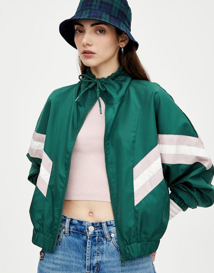 Cazadora con diseño de paneles en diagonal en mangas y hombros, cierre de cremallera y bajo elástico (19,99 euros).