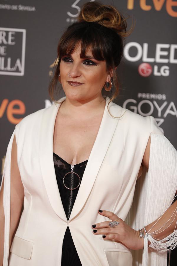 El moño alto de construcción messy se equilibra con un flequillo que enmarca y define la parte superior del rostro.