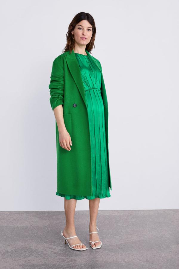 Abrigo de solapa en color verde (99,95 euros) con vestido plisado a juego (59,95 euros).