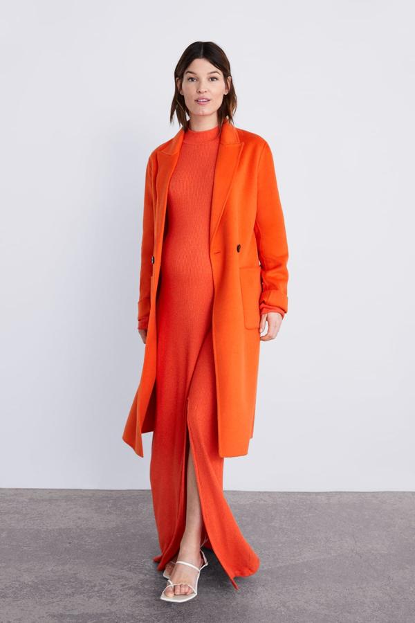 Abrigo masculino en color flúor (99,95 euros) con vestido de canalé naranja con abertura (22,95 euros).