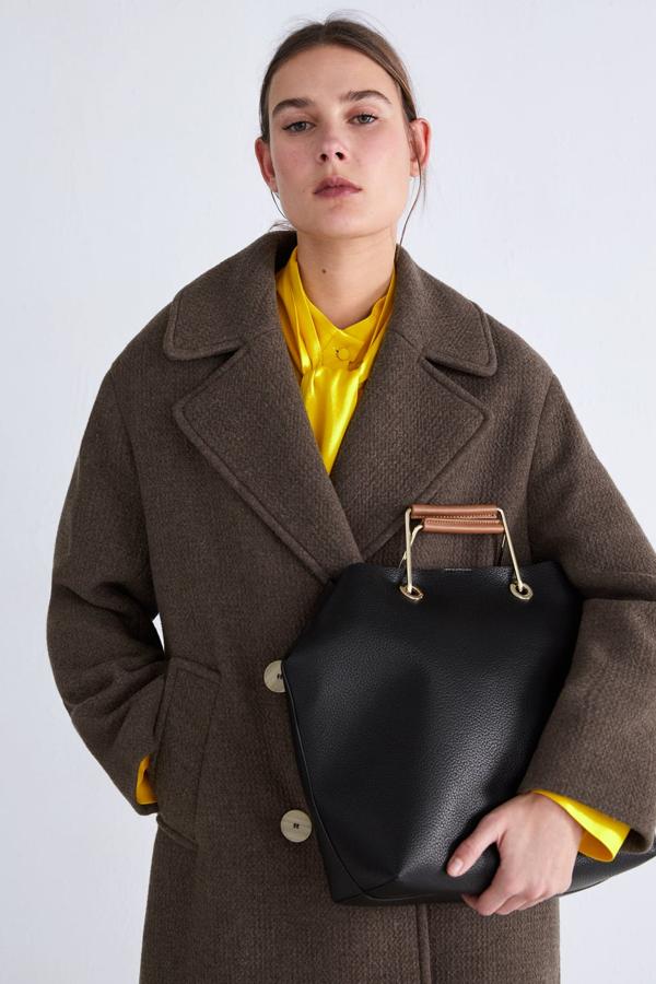 Shopper disponible en varios colores, negro y combinado, con asas de mano metálicas con detalle acolchado. Incluye un neceser interior extraíble con forro y cierre mediante cremallera. El bolso cierra mediante imán (25,95 euros).