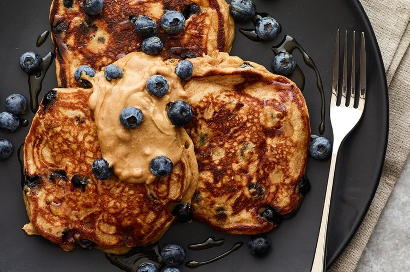 2 huevos grandes3/4 taza de yogur griego bajo en grasa1 1/2 cucharadas de miel, divididas1/2 cucharadita de extracto de vainilla1/2 taza de harina de trigo integral1 cucharadita de polvo para hornear1 pizca de sal1/4 cucharadita de canela1 taza de arándanos frescos (o congelados, descongelados)2 cucharadas de mantequilla de maní natural, divididaBate en un bol los huevos. Agrega el yogur, 1/2 cucharada de miel y vainilla. En otro tazón, mezcla la harina, el polvo de hornear, la sal y la canela. Agrega los ingredientes secos al mojado y revuelve para combinar. Agrega 1/2 taza de arándanos. En una sartén grande antiadherente cubierta con aceite en aerosol a fuego medio-bajo, deja caer la masa hasta formar una tortita. Cocina hasta que la parte inferior esté dorada y se formen burbujas en la parte superior, aproximadamente 3 minutos. Voltea y cocina unos 3 minutos más. Repite la operación con la masa restante. Cubre cada porción con 1/2 cucharada de miel, 1 cucharada de mantequilla de maní y 1/4 taza de arándanos.