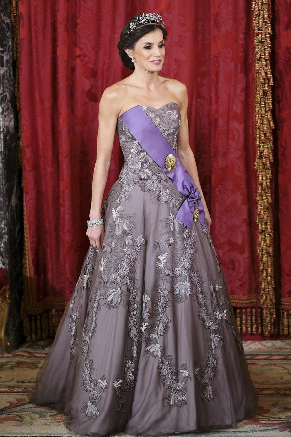 El vestido de la Reina, que le sigue sentando como un guante ocho años después de estrenarlo, es un diseño de corte princesa y escote palabra de honor firmado por Felipe Varela, una pieza realizada en muselina y tul gris lavanda con bordados joya en forma de ramilletes de flores.