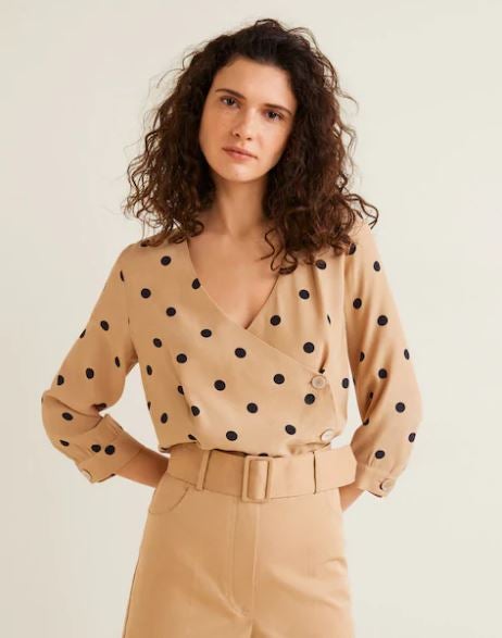 Esta blusa de Mango traslada los botones a un lateral y el resultado es de 10. Además, el estampado de lunares es tendencia esta temporada. (25,95 euros)
