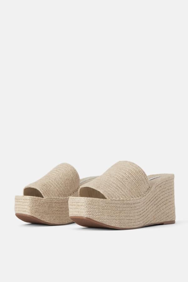 Sandalia de color natural y fabricada totalmente con materiales naturales, la mayor parte en yute. El diseño consta de una tira ancha en la parte delantera y una gran cuña con plataforma (39,95 euros).