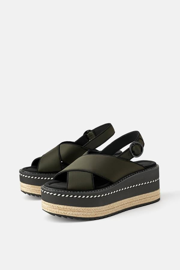 Cuña de color kaki con dos tiras anchas cruzadas en tejido técnico y pespuntes en todo su contorno. La cuña está confeccionada en una combinación de materiales y texturas y lleva la suela dentada. Cierre mediante una hebilla en el tobillo (39,95 euros).