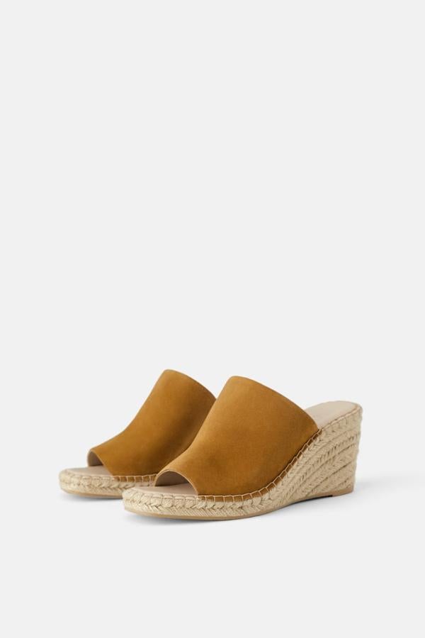 Sandalias de piel de color cuero, con una gran tira en serraje color mostaza. La cuña forrada es de yute (39,95 euros).