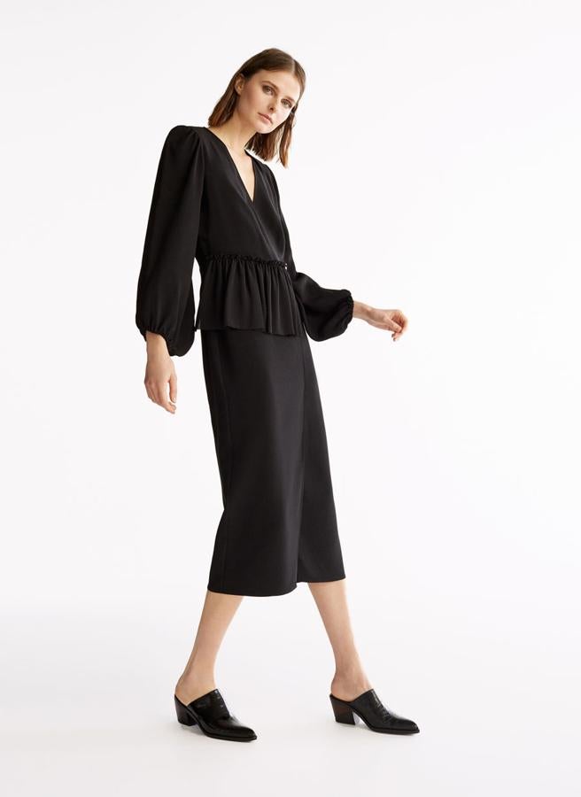 Vestido negro midi, con volante efecto peplum y cerrado con botón dorado, que antes estaba a 159 euros y se ha quedado en 111,30.