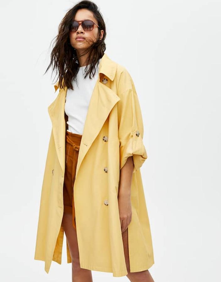 Trench oversize con abertura lateral, bolsillos, cierre de botones en contraste y con la manga vuelta con botón (Pull&Bear, 39,99 euros).