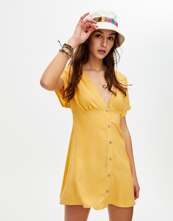 Mini vestido amarillo con estampado de lunares en blanco, de Pull&Bear (19.99 euros).