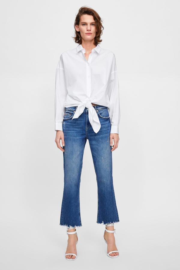 En una combinación clásica con vaqueros, pero con el 'twist' de anudar la camisa a la cintura (19.95 euros en Zara).