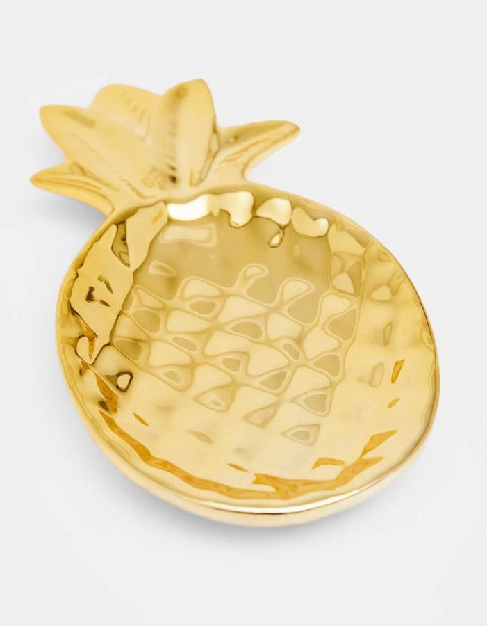 Deja de tirar las llaves a discreción sobre el mueble de la entrada, que después no las encuentras. O de buscar un sinfín de elementos decorativos para la mesita del salón que no pasarían el filtro de la mismísima Marie Kondo. Lo único que necesita tu casa es este coqueto platito piña dorado muy acorde con la estación, por 5,99 €.