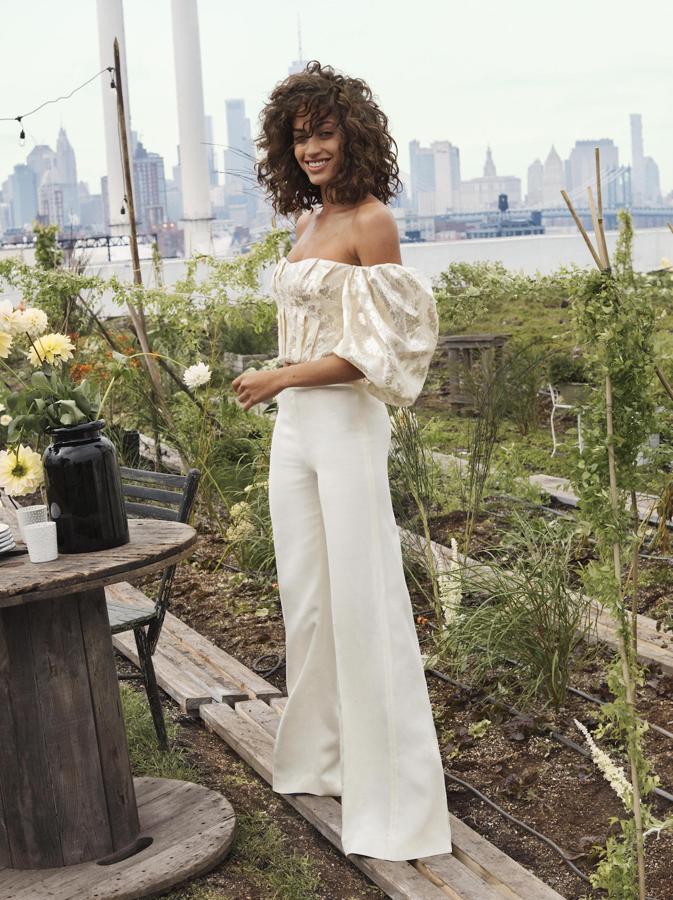 Maravilloso conjunto de pantalones acampanados en blanco roto (89,99 euros) con un top sin hombros, con un estampado estilo brocado, mangas abullonadas, jaretas y escote corazón (129 euros). Está confeccionado en tencel y fibra de naranja.