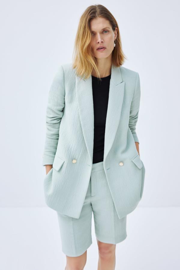 Aunque este traje con tejido texturizado en azul aguamarina nos parece súper elegante... La chaqueta con botones de perla cuesta 49.95 euros en Zara, y las bermudas, 25.95 euros.