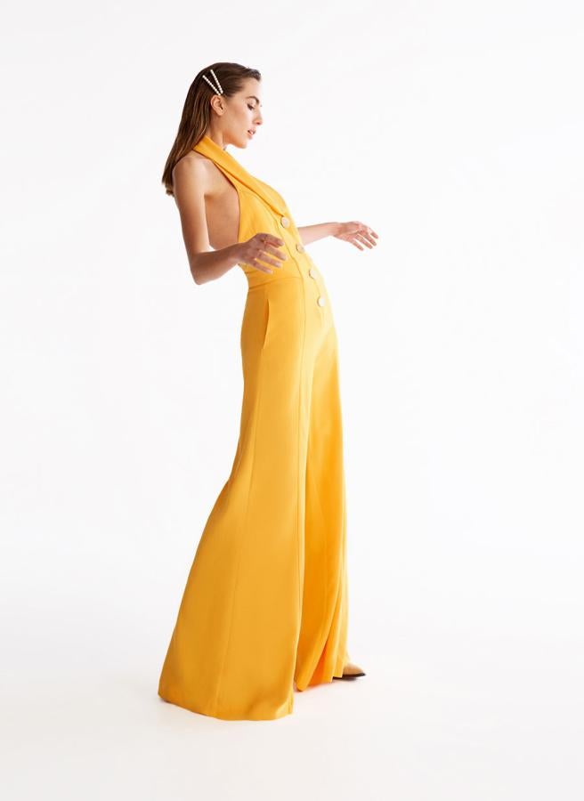 Mono largo fluido en color amarillo, con escote en la espalda y con detalle de botones en la parte frontal, 159 euros.
