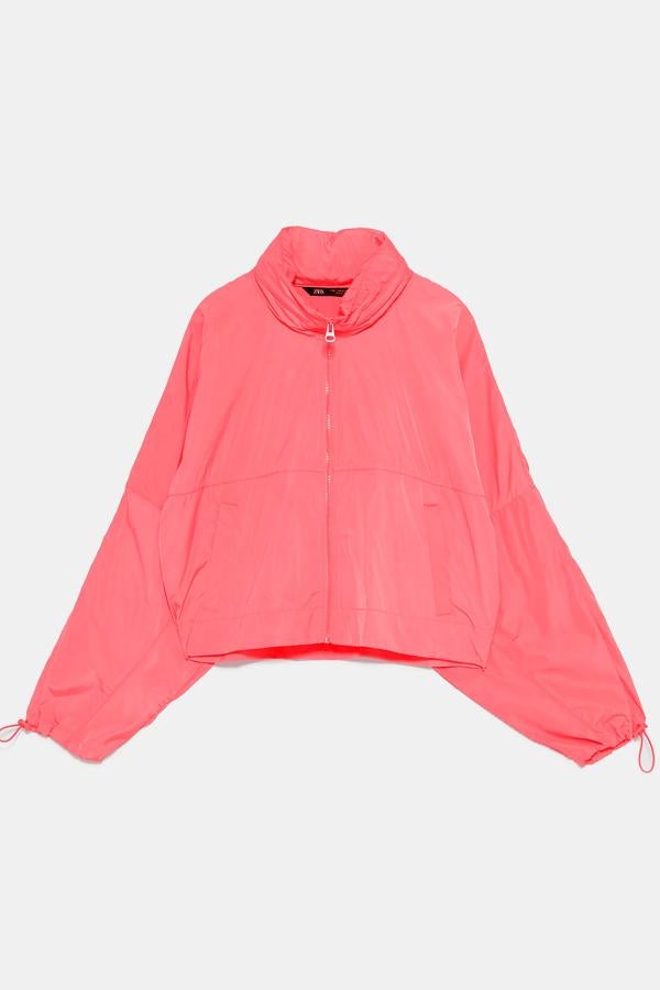 Chubasquero water resistant de cuello subido y capucha ajustable oculta con cremallera. Manga larga acabada en elástico ajustable, bolsillos laterales y bolsillo en espalda convertible en bolsa - mochila para transportarlo (Zara, 25,95 euros).