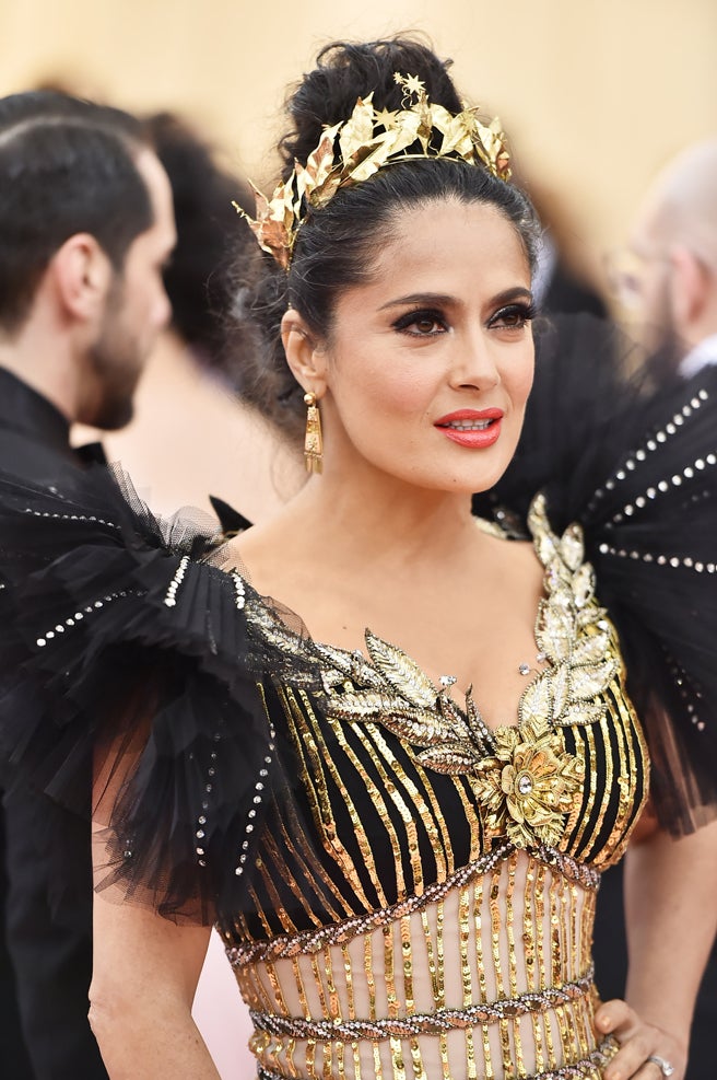 Salma Hayek estaba radiante con un maquillaje firmado por Matthew Vanleeuwen. Ojos muy potentes en negro y un color de labios satinados que le favorece. Pero si hay algo que sin duda vamos a destacar es su peinado. Un recogido alto con un tocado dorado estilo romano y un detalle que no hemos dejado pasar por alto: sus canas. Esas que tanto debate han creado en los últimos meses  desde que las lució la Reina Letizia  en público. ¡Viva lo natural!