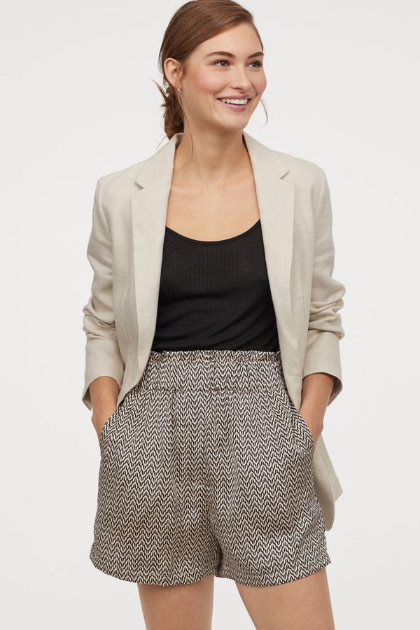 Pantalón corto de tela con el talle alto y la cintura abullonada gracias a un elástico ancho. Lleva un cierre decorativo y bolsillos en las costuras laterales con detalles de metal (19,99 euros).