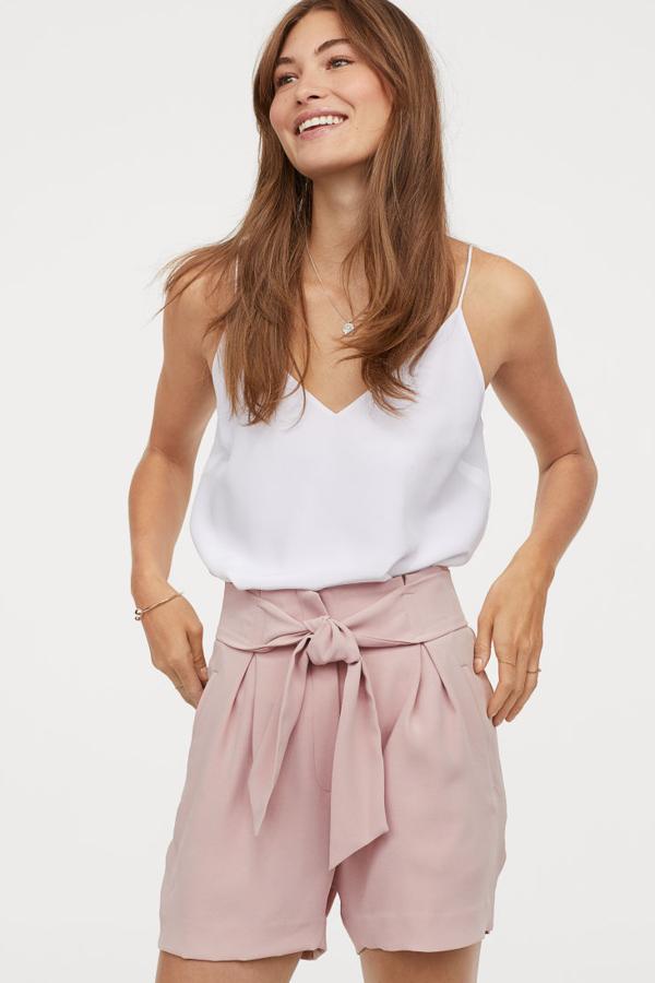 Pantalón corto de tela con pliegues, cinturón de anudar cosido, bolsillos al bies y bolsillos traseros ribeteados. Lleva el talle alto y un cierre con cremallera oculto (24,99 euros).