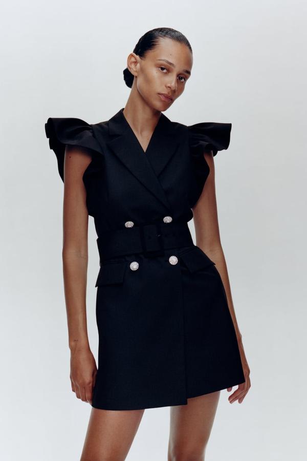 Vestido chaleco mini con cuello, solapa y manga sisa adornada con un volante. Lleva bolsillos delanteros de solapa y un cinturón del mismo tejido con una hebilla forrada. Cierra en el frontal con botones joya. Este vestido también se sale del presupuesto de los 50 euros: 79,95.