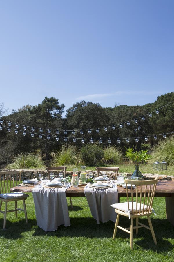 Los materiales rústicos, la madera, los tejidos naturales en colores neutros... y esas luces de verbena. Esta propuesta de comedor exterior de Muy Mucho es pura inspiración para el verano.