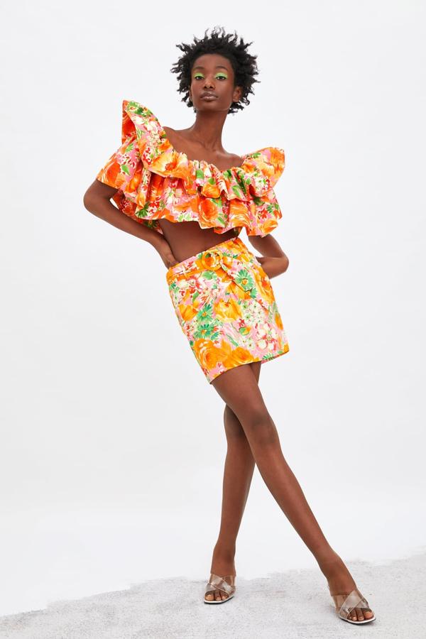 Top corto de escote amplio y detalle de volantes de Zara (22,95 euros) a juego con la minialda de tiro alto y bolsillos laterales (Zara, 25,95 euros). Lleva un adorno de pliegues en frontal y un cinturón en mismo tejido con hebilla forrada.