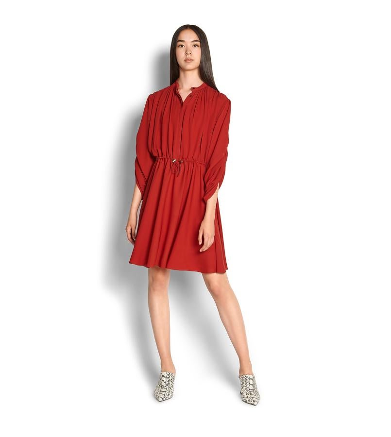 El vestido de Salvatore Ferragamo (que en el lookbook también lo combinan con zapatos de estampado pitón, como la Reina) es un diseño de la colección primavera verano 2019 en georgette de seda en color rojo ladrillo, con cuello mandarín, corpiño plisado y manga francesa. ¿Su precio? Ni más ni menos que 1.650 euros.