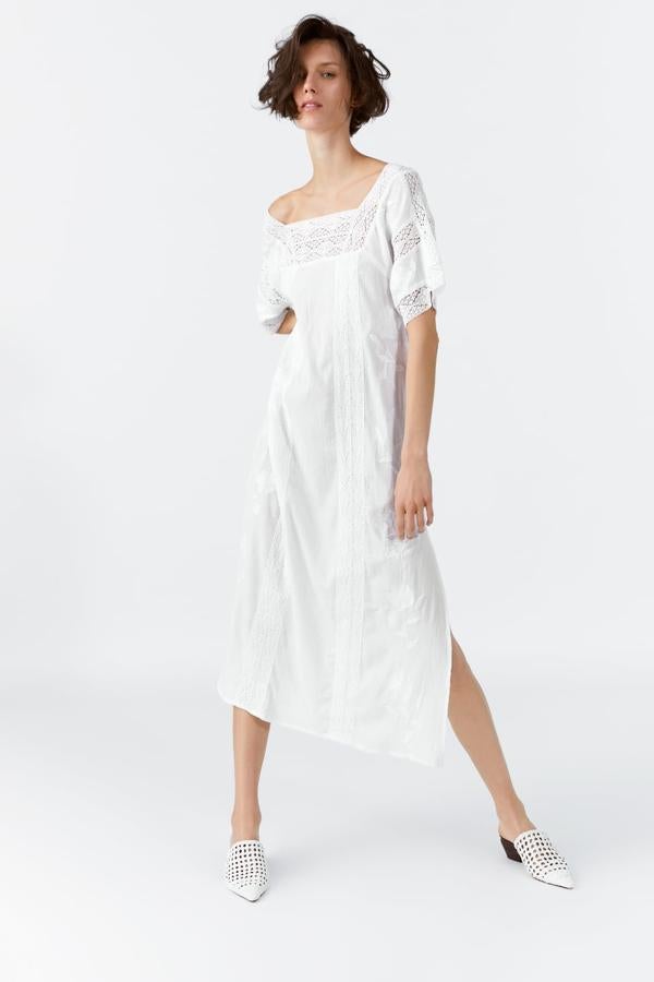 Vestido de escote recto y manga corta, con aplicación de entredós y bordados combinados a tono. Lleva unas aberturas laterales en el bajo (Zara, 39,95 euros).