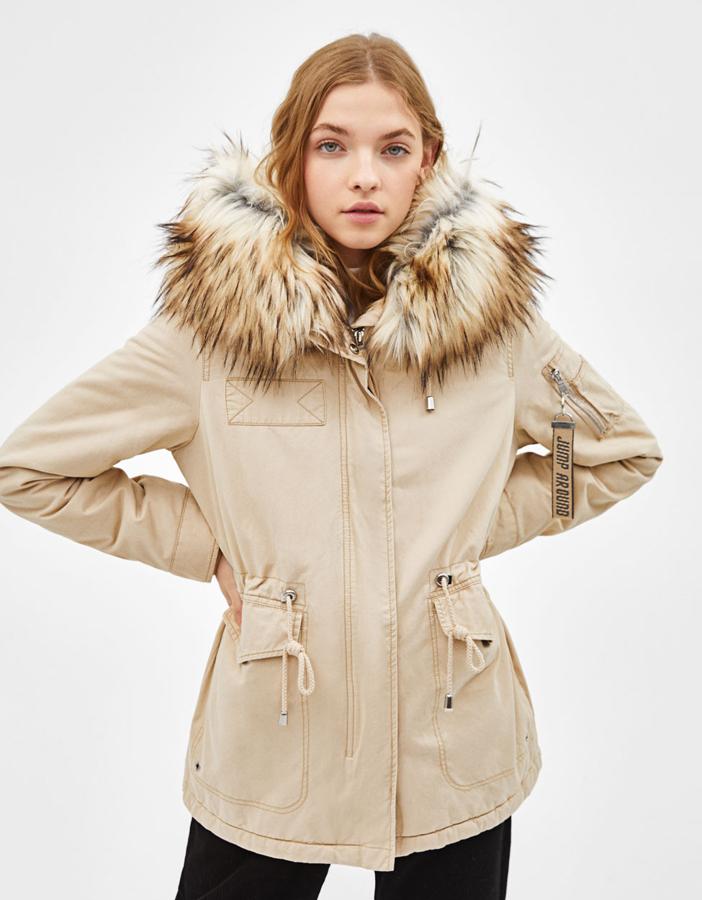 Abrigo tipo parka con el interior forrado de pelo y capucha extraíble. Lleva cintura ajustable, bolsillos laterales y cierre de cremallera y corchetes (Bershka, 24,99 euros).