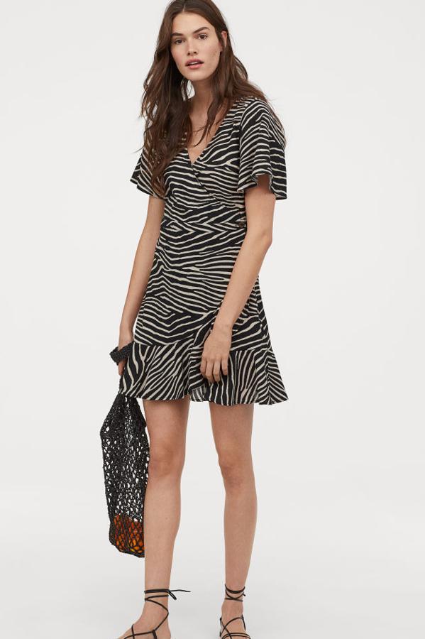 Vestido estampado en crepé de algodón, con mangas cortas amplias, escote de pico y frente cruzado. Lleva una costura en la cintura y un botón en un lateral y se adorna con un volante en el bajo (H&M, 29,99 euros).