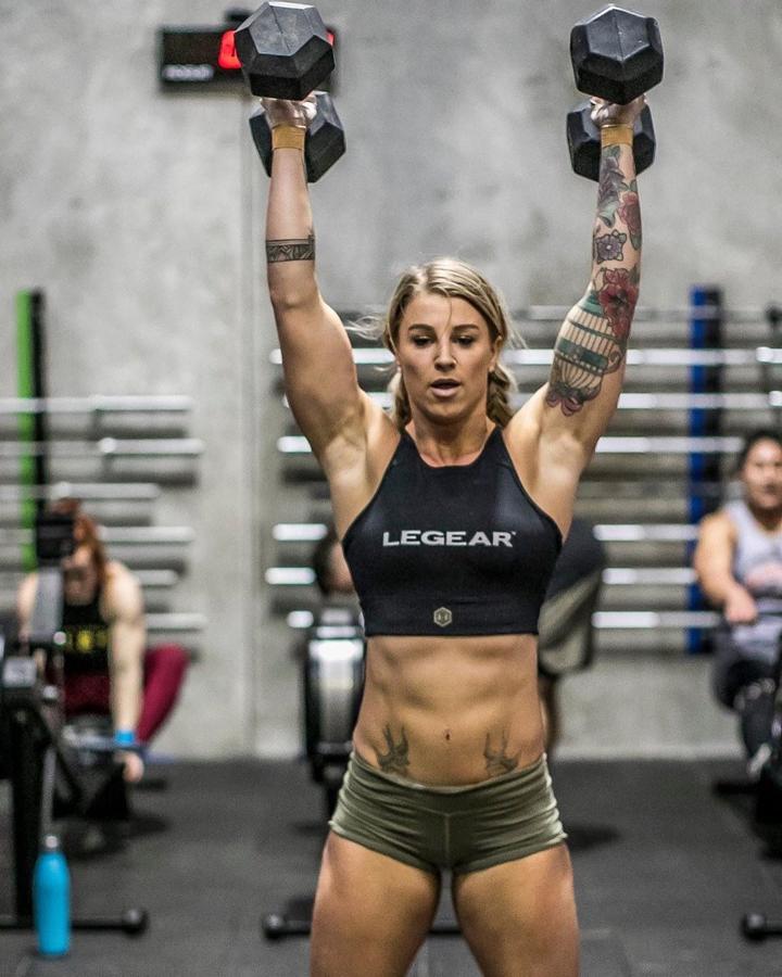 Ponte de pie con los pies separados a la distancia de los hombros, sujeta un par de mancuernas por encima de los hombros con las palmas enfrentadas. Baja las caderas y ponte de cuclillas hasta que los muslos estén en paralelo al suelo. En un solo movimiento, estira las piernas y ponte de pie mientras levantas las mancuernas por encima de la cabeza. Haz una pausa y luego baja las mancuernas a la posición de inicio.
