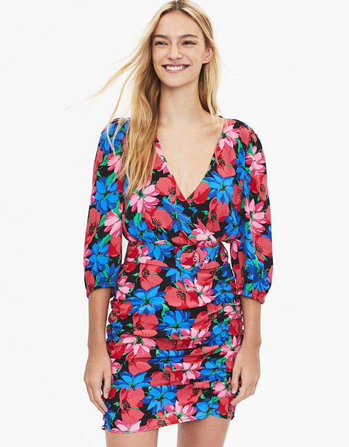 Vestido corto drapeado con manga 3/4 y escote cruzado. Lleva la cintura ajustada por un cinturón con hebilla en el mismo tejido, estampado de flores (Bershka, 29,99 euros).