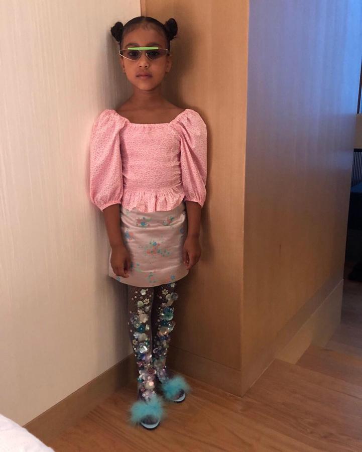 La hija de Kim Kardashian no duda en apostar por los accesorios más inverosímiles que combina de la forma más loca. En este look lleva unas gafas de inspiración deportiva con unas medias de rejilla cuajadas de flores y unas sandalias de plumas turquesa.