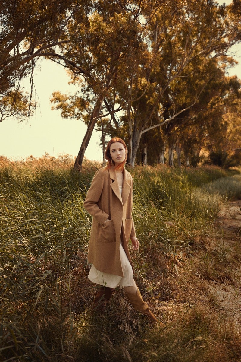 Vestido en color beige con botones, abrigo de color camal con solapas y botas altas estilo cow boy. Todo de Lefties.