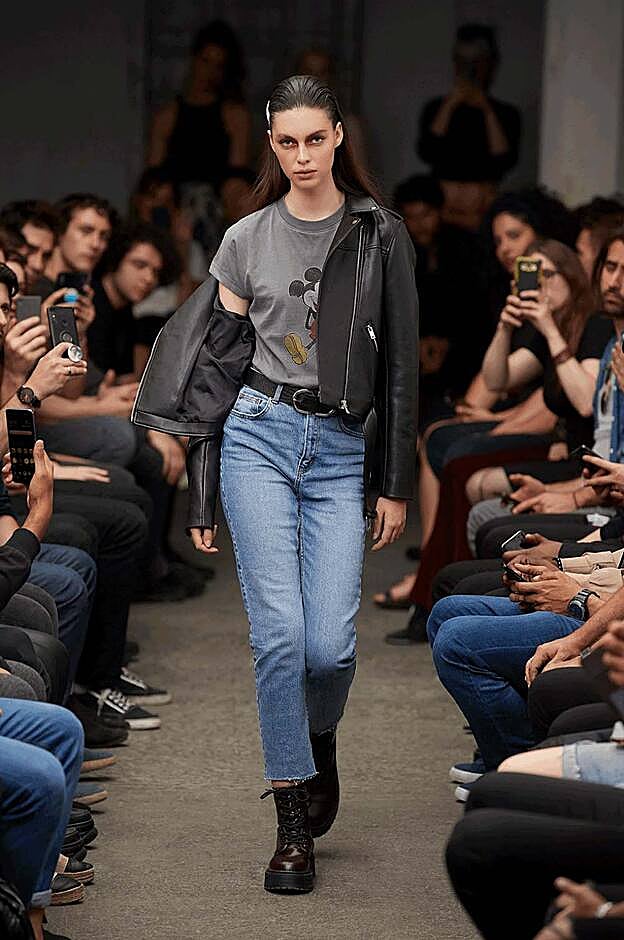 Cazadora motera negra 25 euros, camiseta de Mickey Mouse 10 euros, vaqueros 17 euros, cinturón ancho doble con hebilla de infinito 5 euros, botines negros 21 euros.