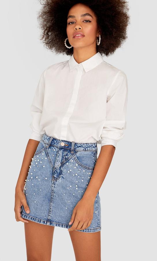 Con unas costuras estratégicas que delgazan la figura, estamos in love con esta minifalda vaquera adornada con perlas de Stradivarius (25,99 euros).