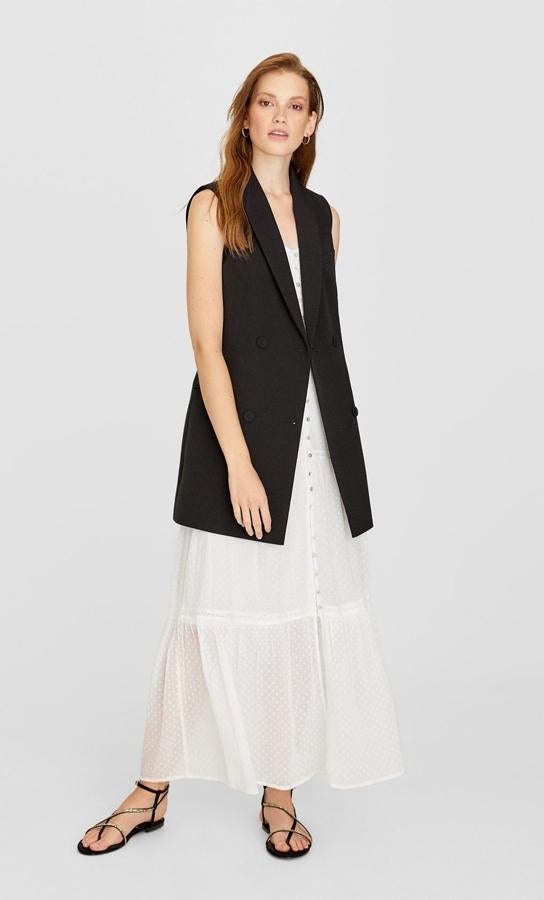 Si te resistes a guardar en el trastero tus vestidos de verano, prueba a llevarlos unas semanas más a la oficina. En Stradivarius nos proponen combinarlos con un sobrio maxi chaleco negro (29.99 euros), y la idea nos encanta.