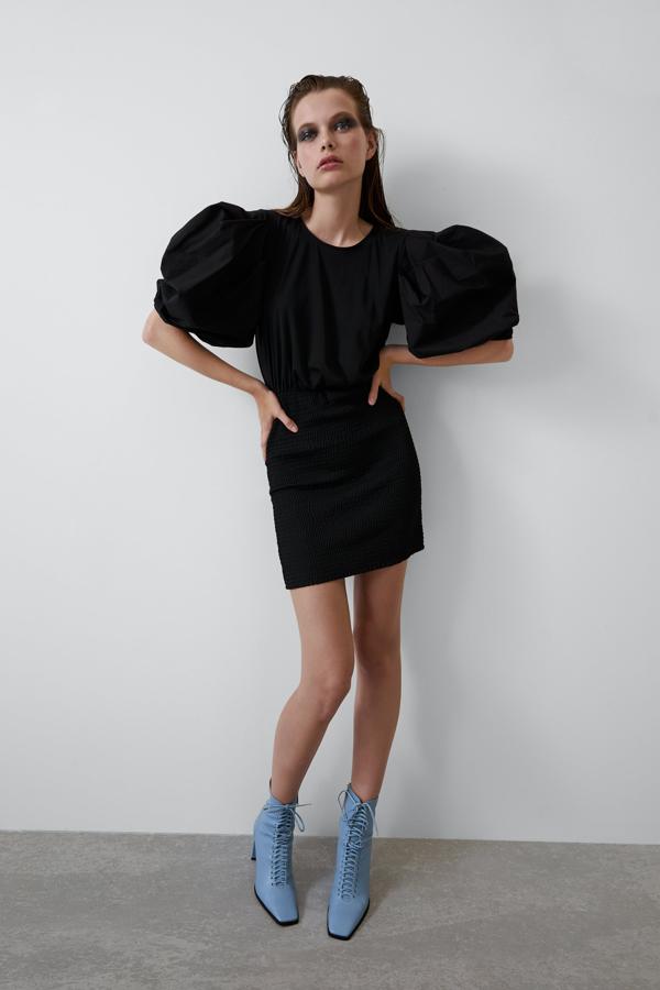 Mini vestido negro con falda microplisada y cuerpo con mangas en volumen de Zara (25.95 euros).