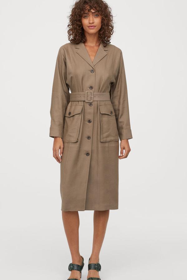 En la colección Premiun de H&M encontramos este diseño confeccionado en sarga suave, mezcla de lino y lyocell, con mangas dolman con puños sencillos, cinturón ajustable de quita y pon con hebilla revestida de tela y bolsillos delanteros con solapa y botón (H&M, 89,99 euros).